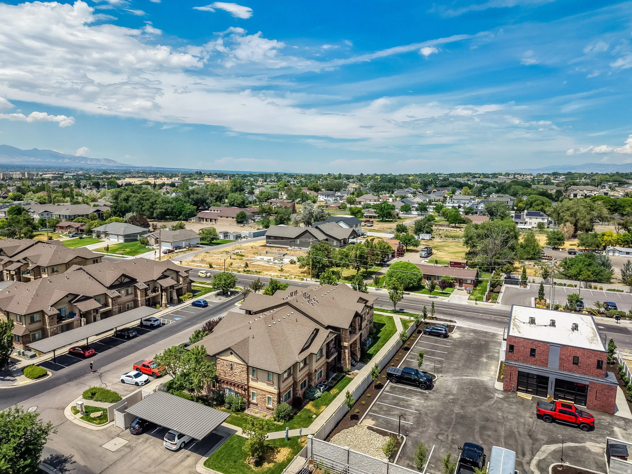 Expansive aerial perspective showcasing a residential community with multi-story buildings, covered parking structures, and mature landscaping