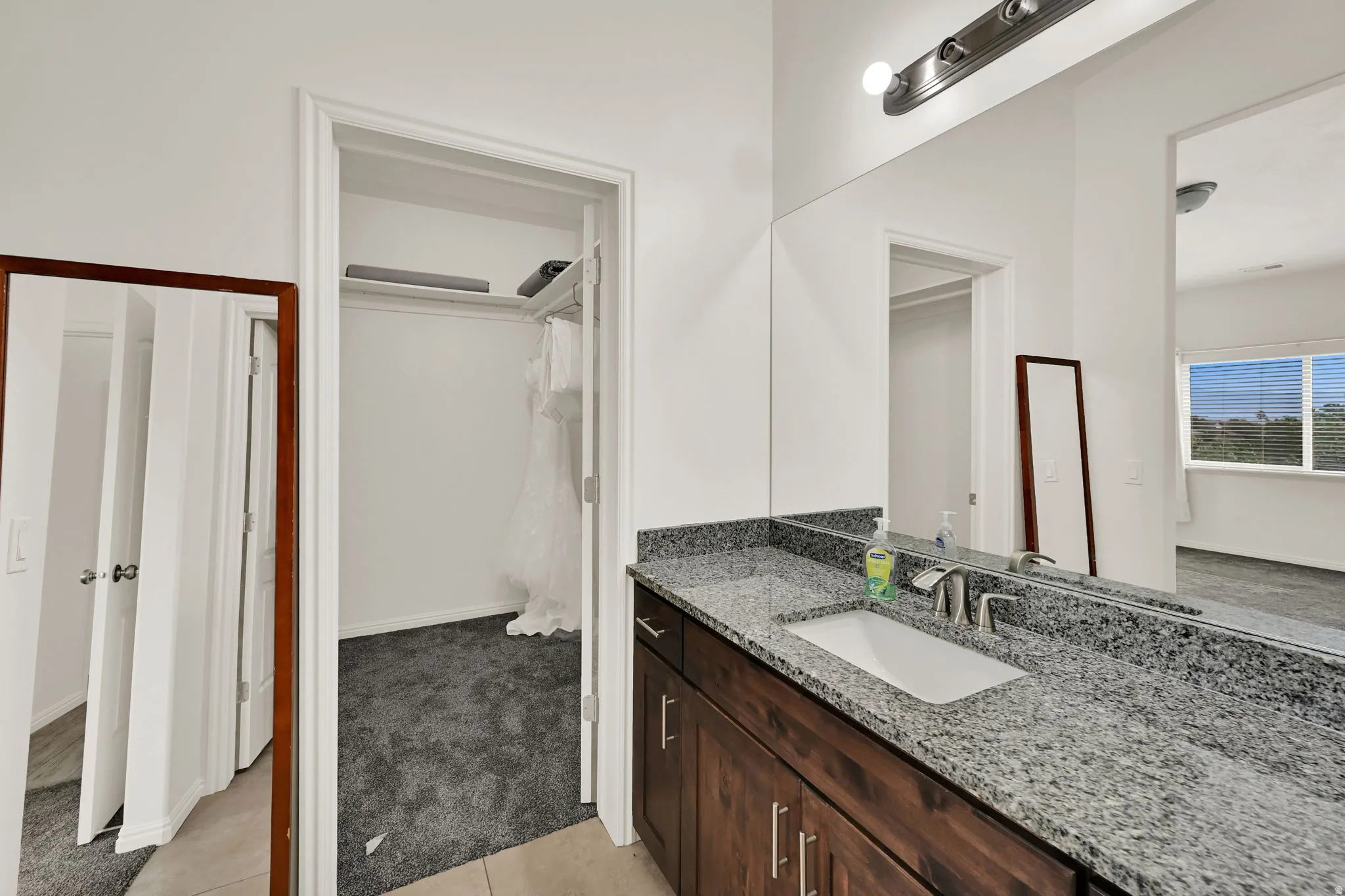 Vanity with a single undermount sink, granite countertop, and dark wood-finish cabinetry with brushed nickel hardware