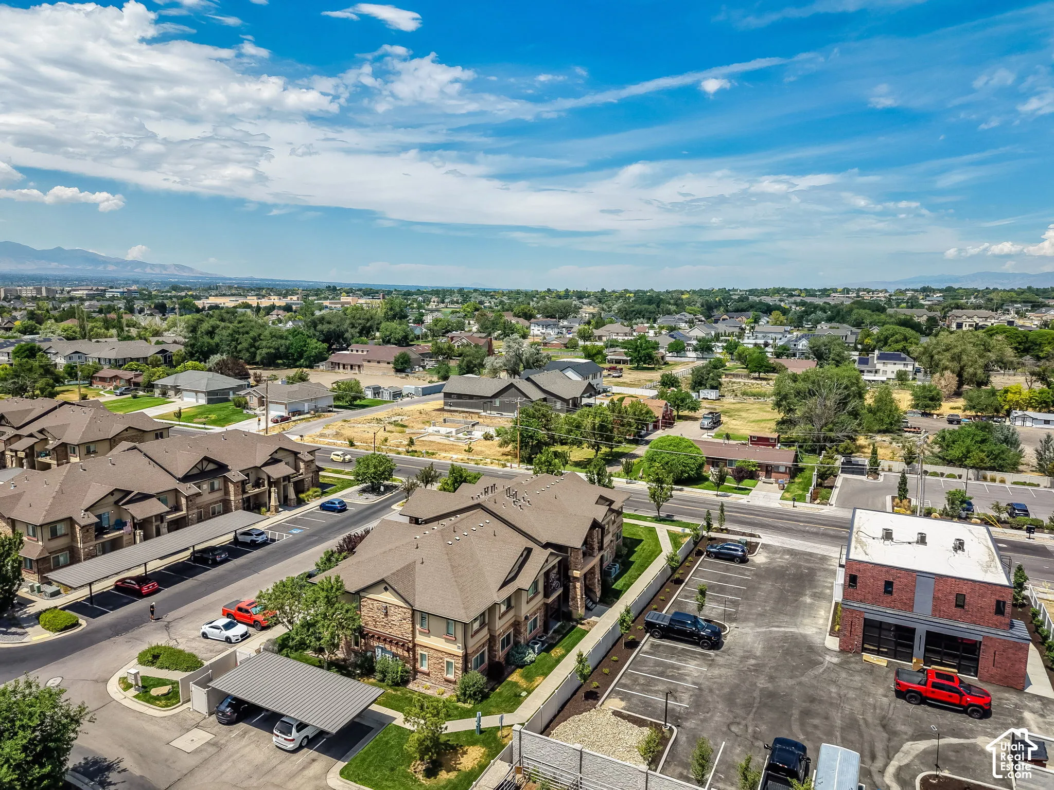 Expansive aerial perspective showcasing a residential community with multi-story buildings, covered parking structures, and mature landscaping