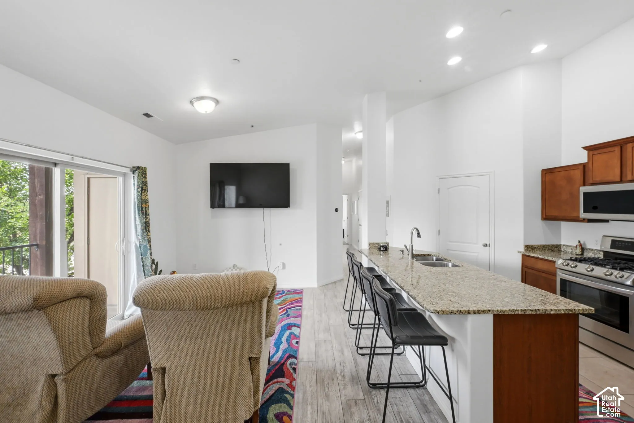 Open-concept living area featuring a kitchen with light-colored countertops, stainless steel appliances, and wood cabinetry