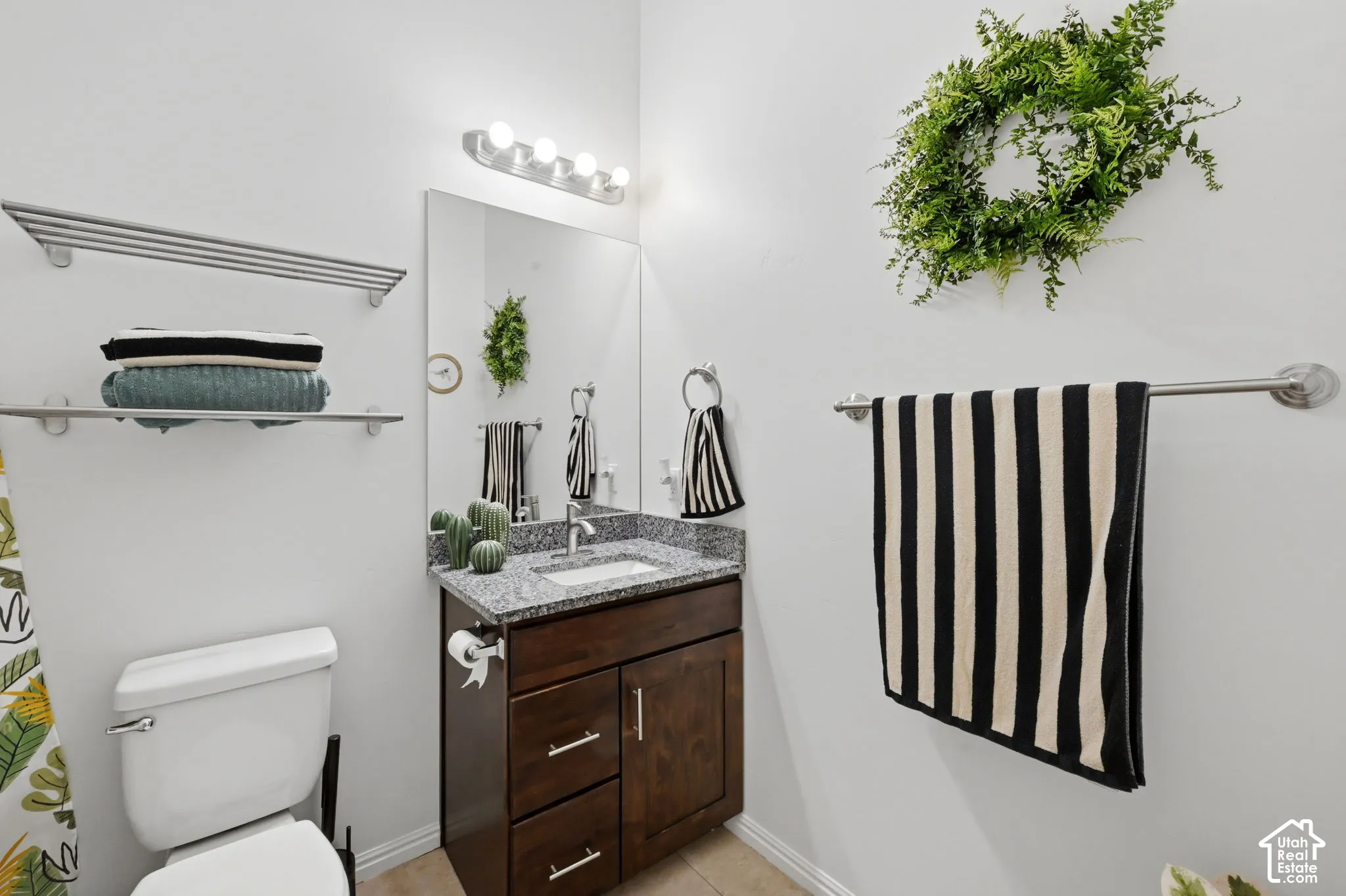 Bathroom featuring a dark wood-finish vanity with a granite countertop and an undermount sink
