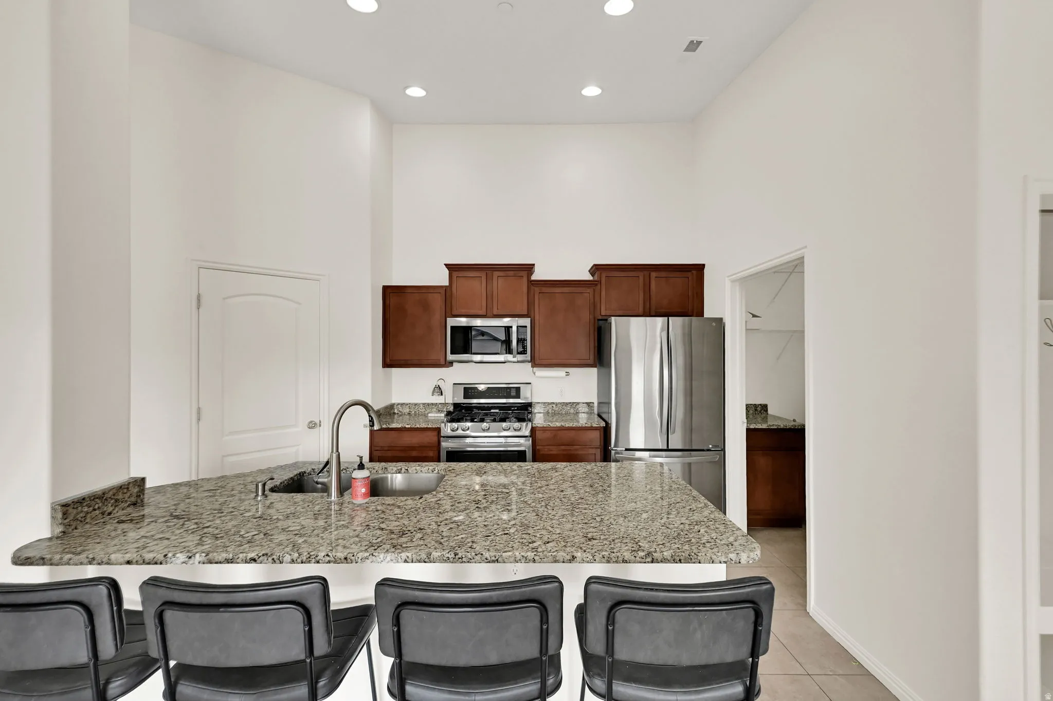 Kitchen featuring a breakfast bar with stone-finish countertop, stainless steel appliances, and recessed lighting