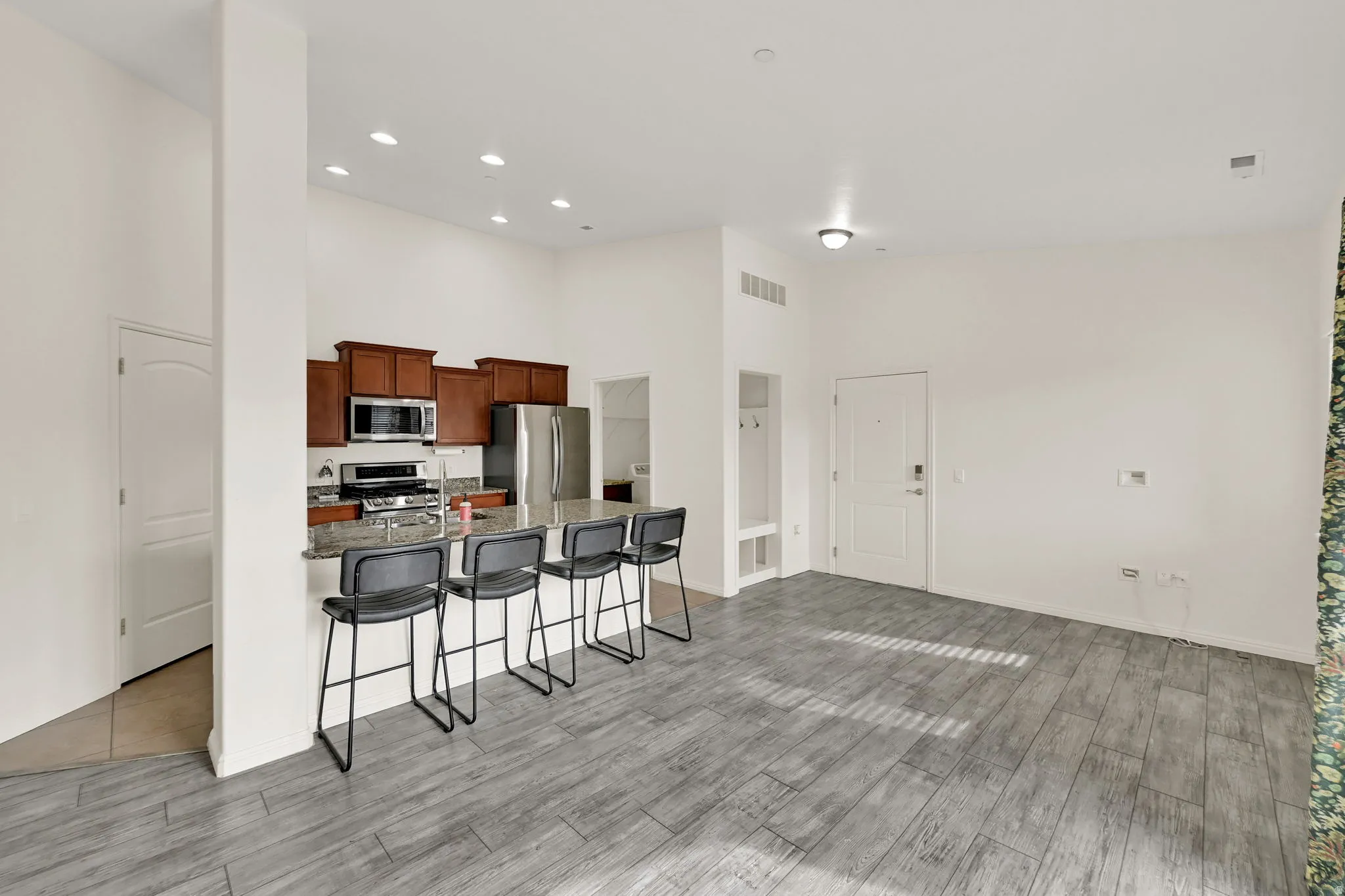 Kitchen featuring wood cabinetry, stainless steel appliances, and a breakfast bar with stone-finish countertops