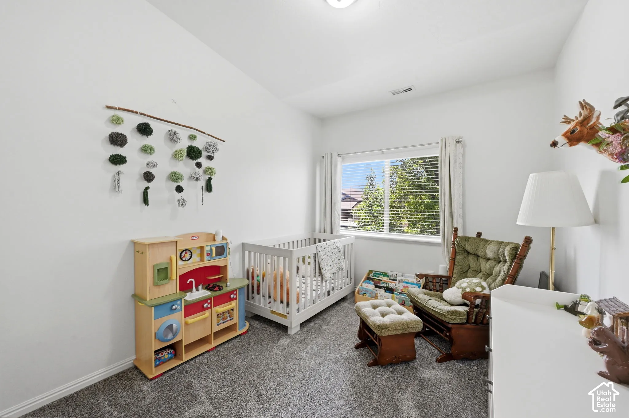 Well-lit room with a window providing natural light, neutral wall colors, and grey carpet flooring