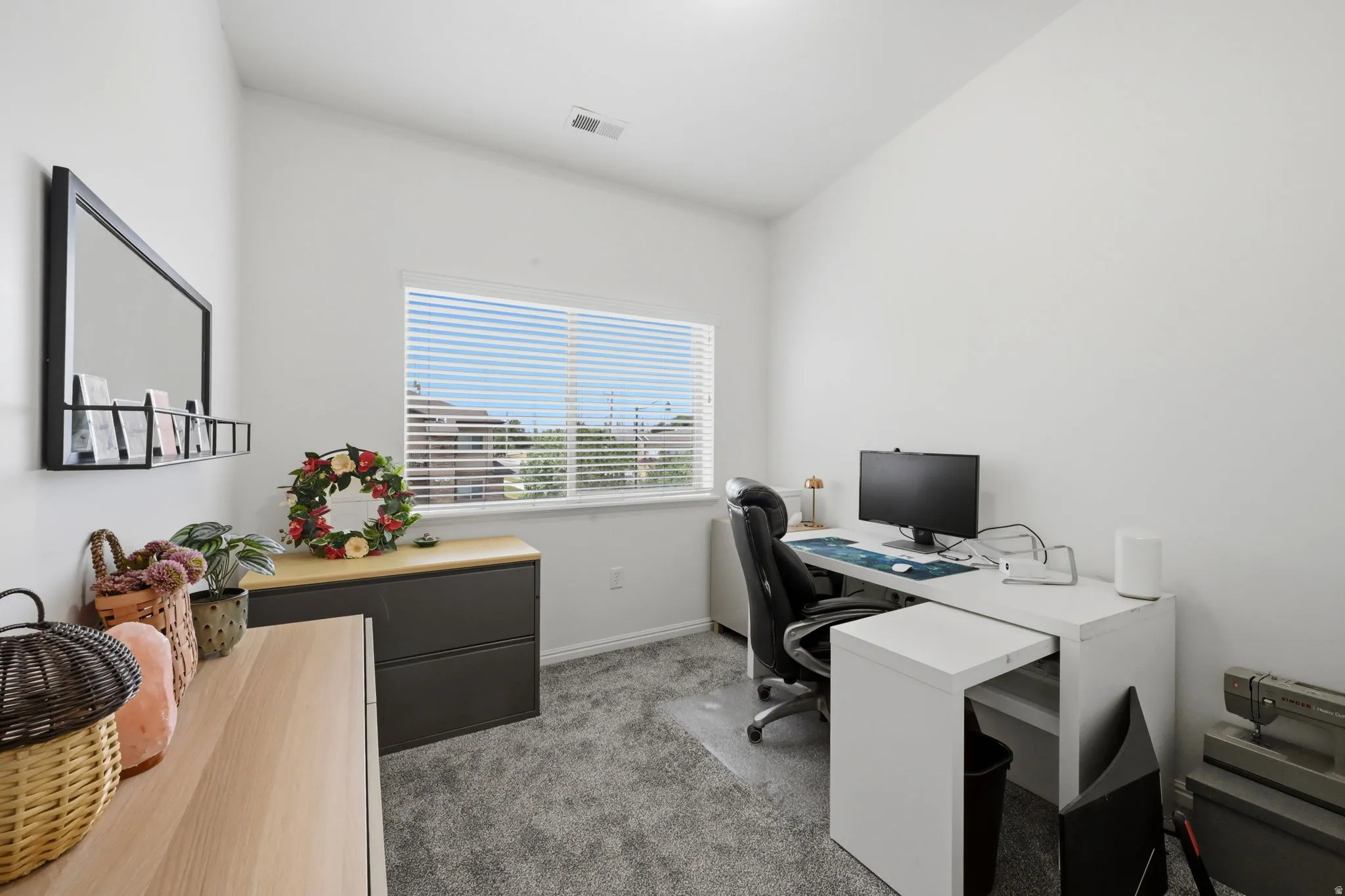 Room featuring a large window with blinds, light gray carpet, and white walls