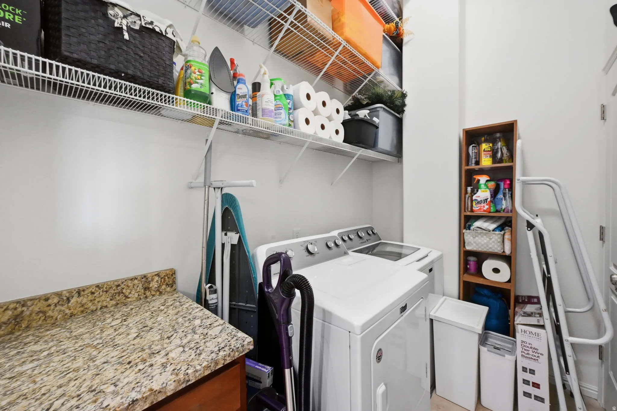 Dedicated laundry area featuring a granite-style countertop, white wire shelving, and a built-in base cabinet