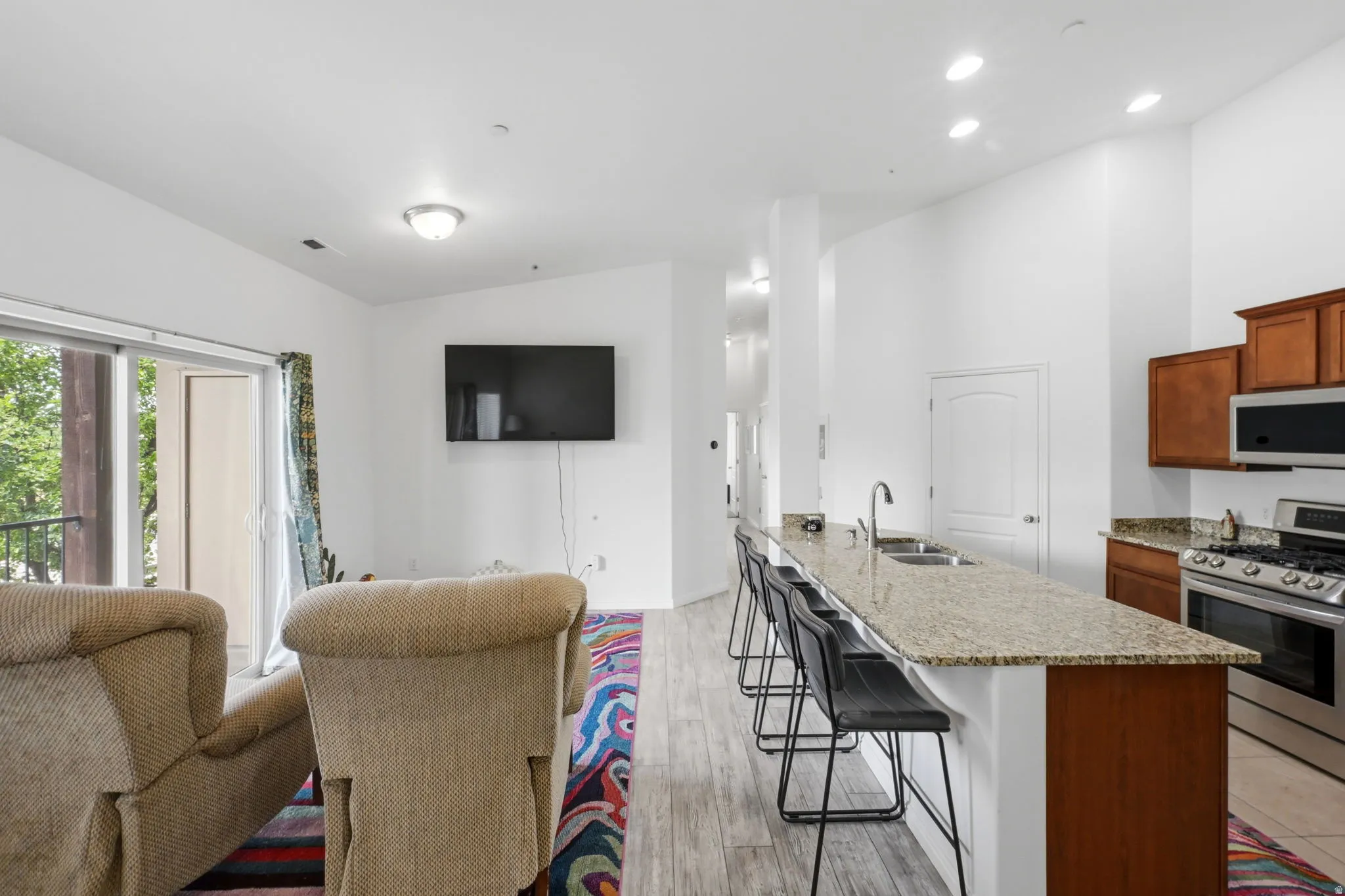 Open-concept living area featuring a kitchen with light-colored countertops, stainless steel appliances, and wood cabinetry