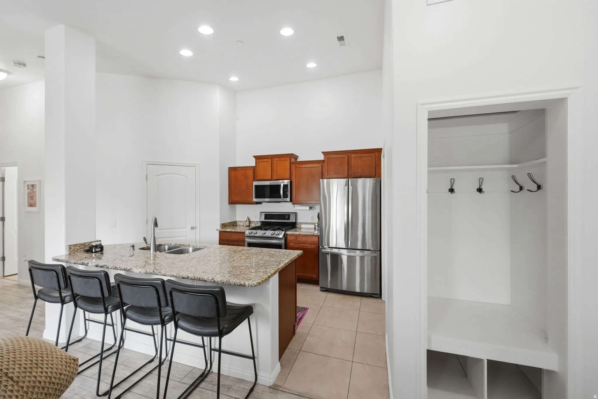 Contemporary kitchen featuring wood cabinetry, stainless steel appliances, and a granite-topped island with an integrated sink