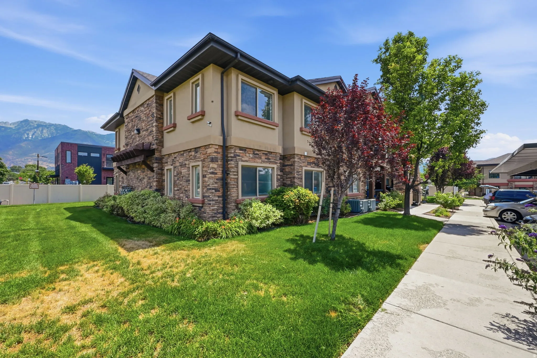 Multi-story exterior featuring a stone and stucco facade, dark trim, and multiple windows