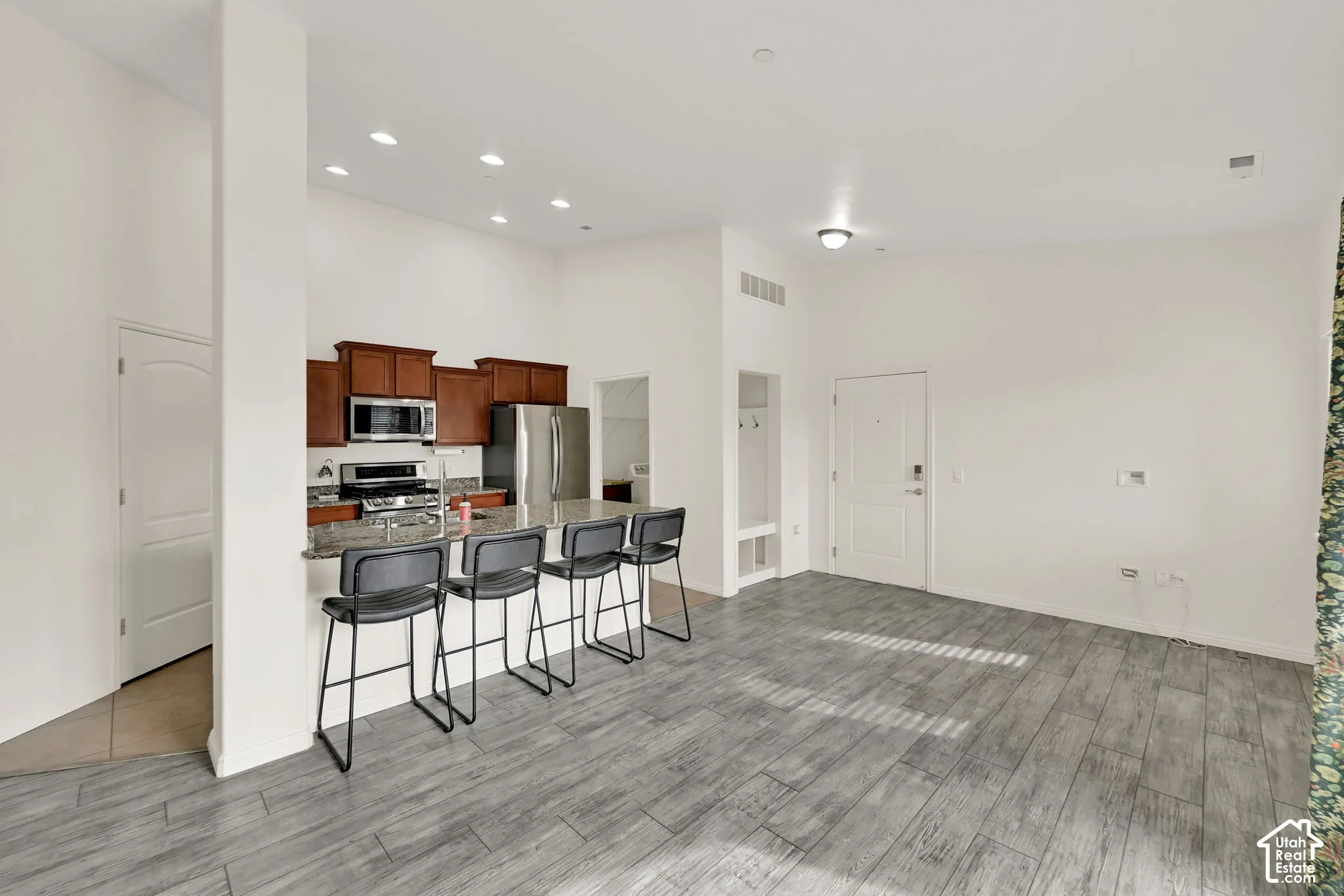 Kitchen featuring wood cabinetry, stainless steel appliances, and a breakfast bar with stone-finish countertops