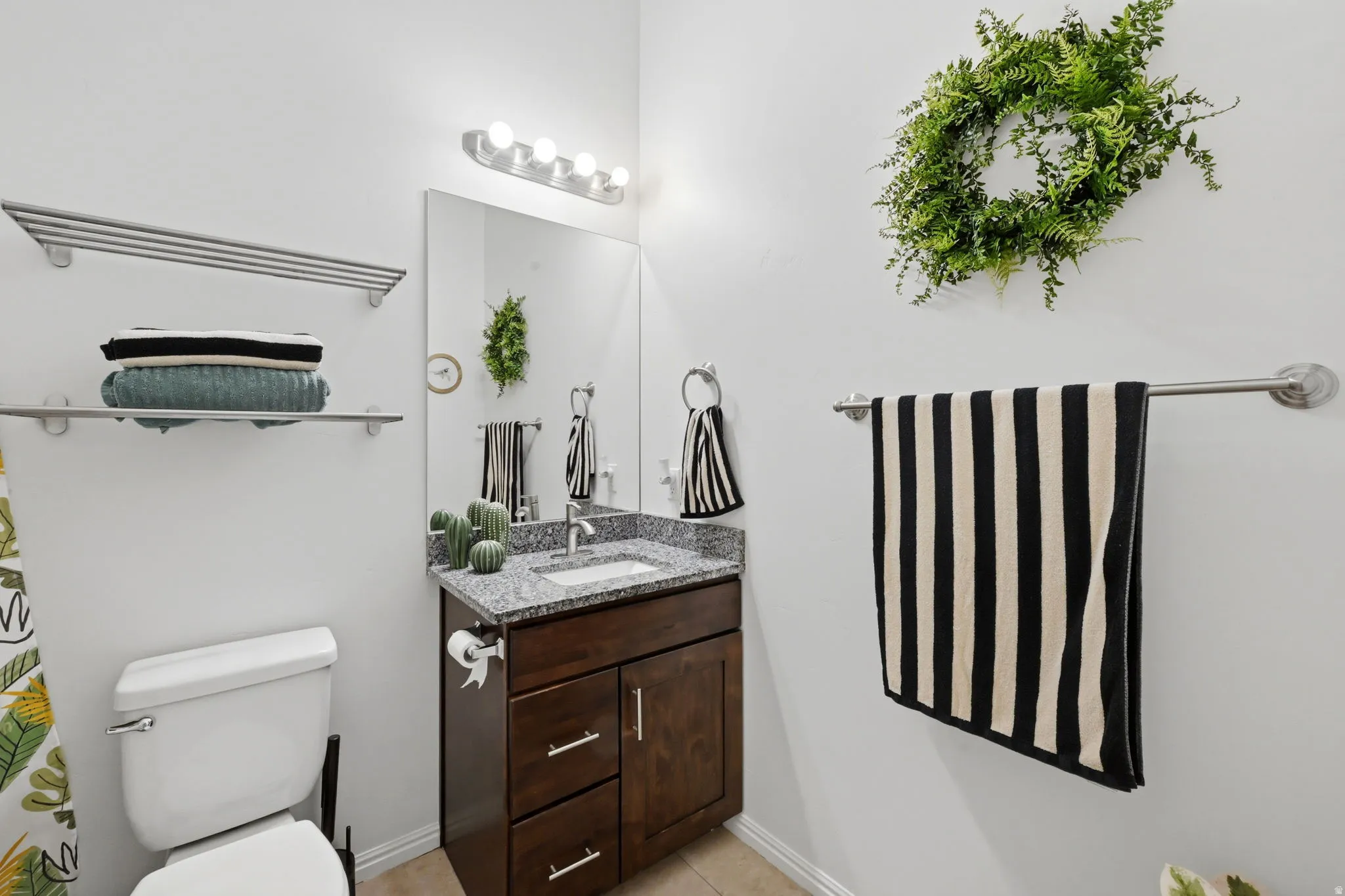 Bathroom featuring a dark wood-finish vanity with a granite countertop and an undermount sink