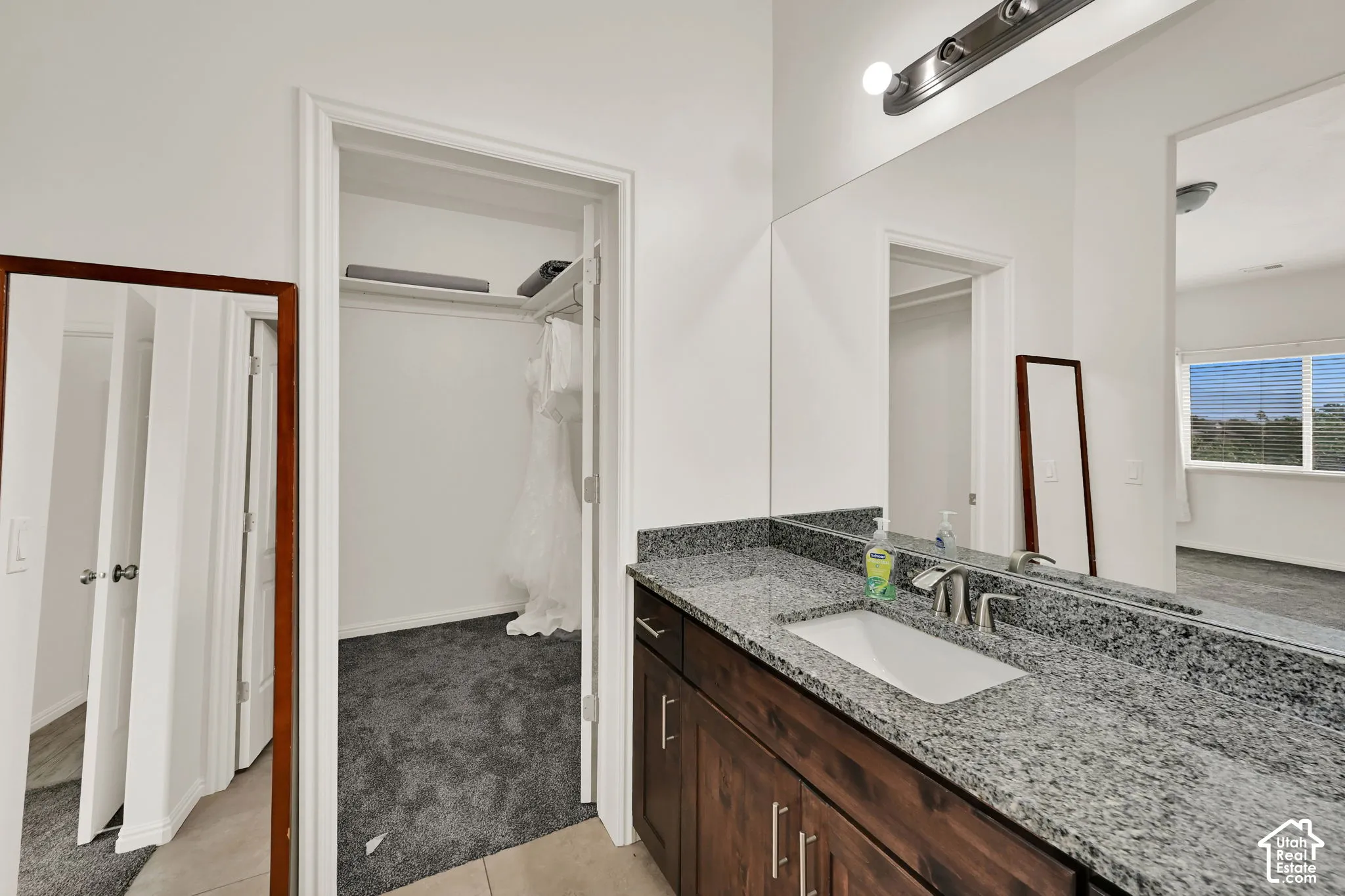 Vanity with a single undermount sink, granite countertop, and dark wood-finish cabinetry with brushed nickel hardware