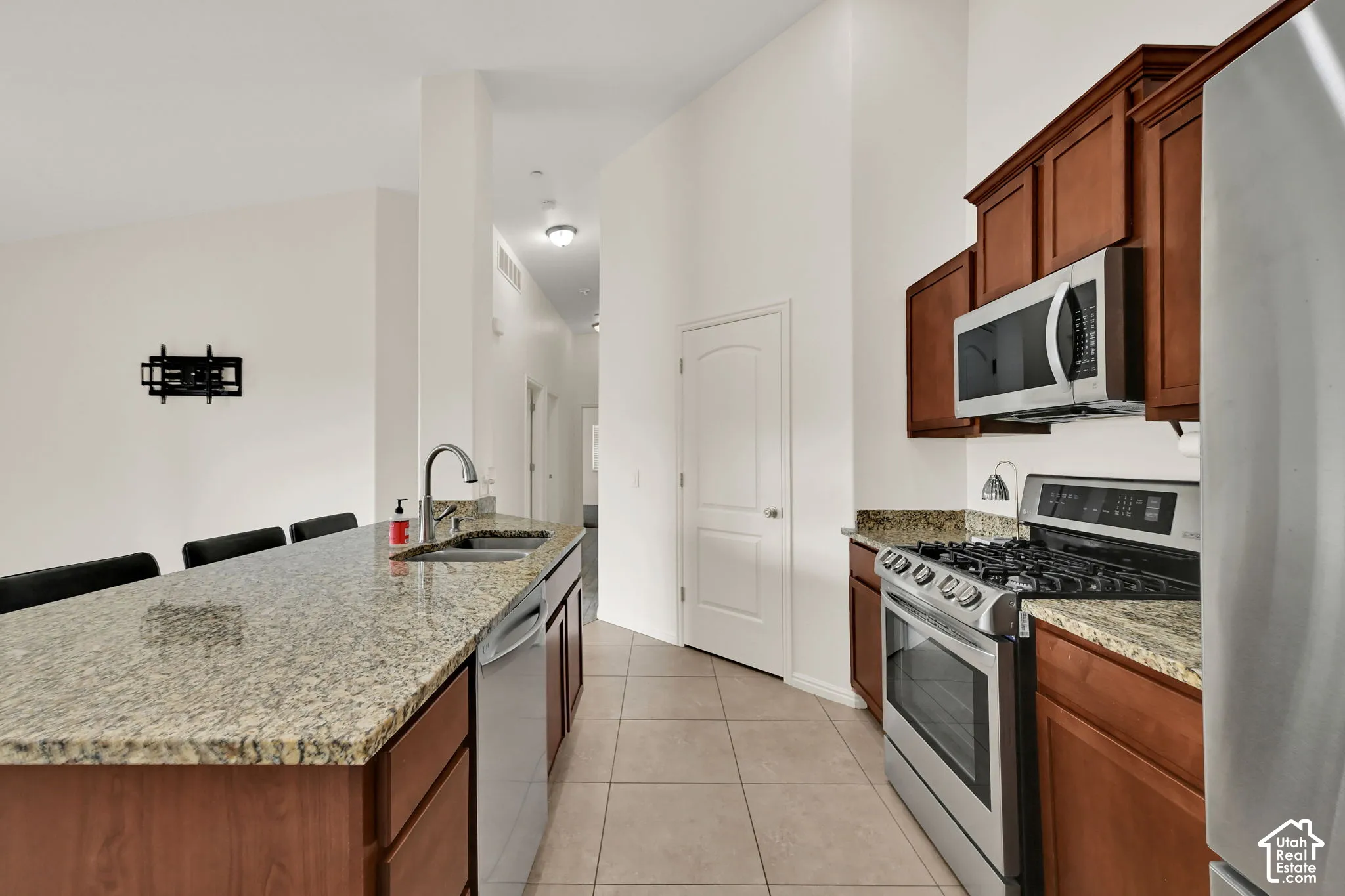 Kitchen featuring wood-finish cabinetry, granite countertops, stainless steel appliances, and tile flooring