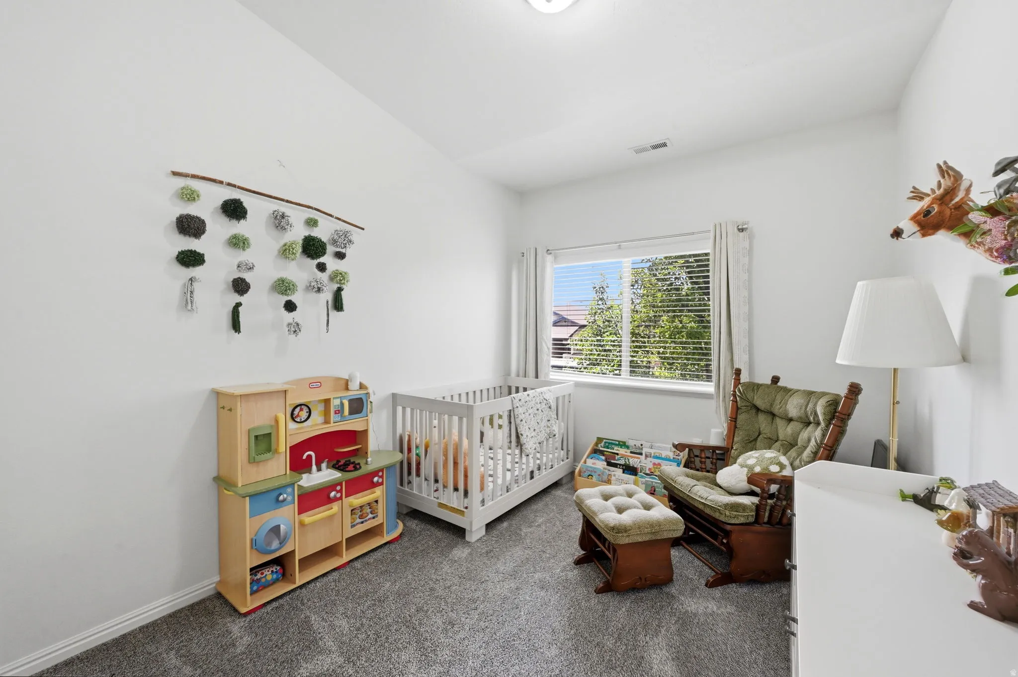 Well-lit room with a window providing natural light, neutral wall colors, and grey carpet flooring