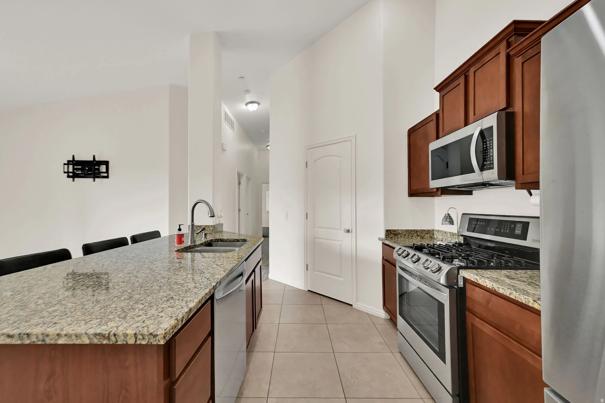 Kitchen featuring wood-finish cabinetry, granite countertops, stainless steel appliances, and tile flooring