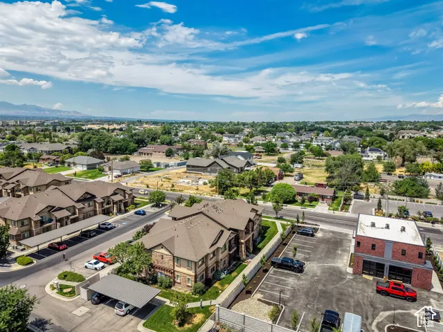 Expansive aerial perspective showcasing a residential community with multi-story buildings, covered parking structures, and mature landscaping