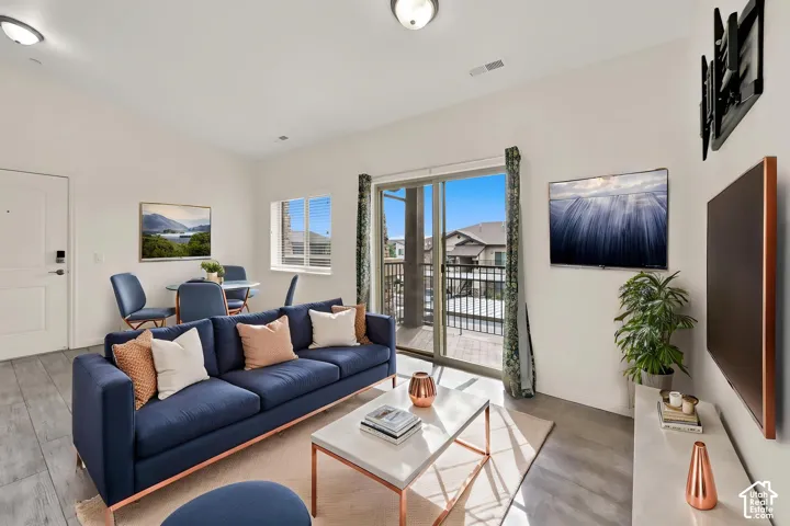 Wood-finish flooring, white walls, recessed lighting, and a sliding glass door to a balcony with black railings
