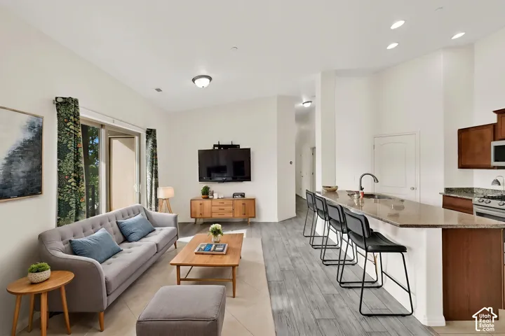 Open-concept living space featuring high ceilings, wood-finish flooring, a kitchen island with seating, and a stainless steel gas range