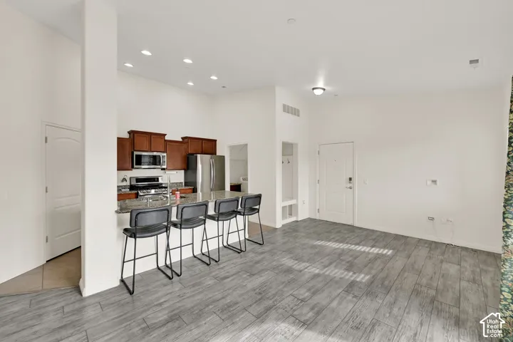 Kitchen featuring wood cabinetry, stainless steel appliances, and a breakfast bar with stone-finish countertops