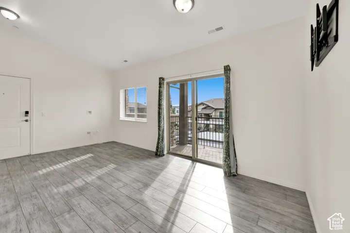 Wood-finish flooring, white walls, built-in wall mount, sliding glass door with balcony, and a window with blinds