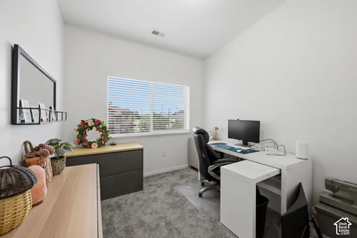 Room featuring a large window with blinds, light gray carpet, and white walls