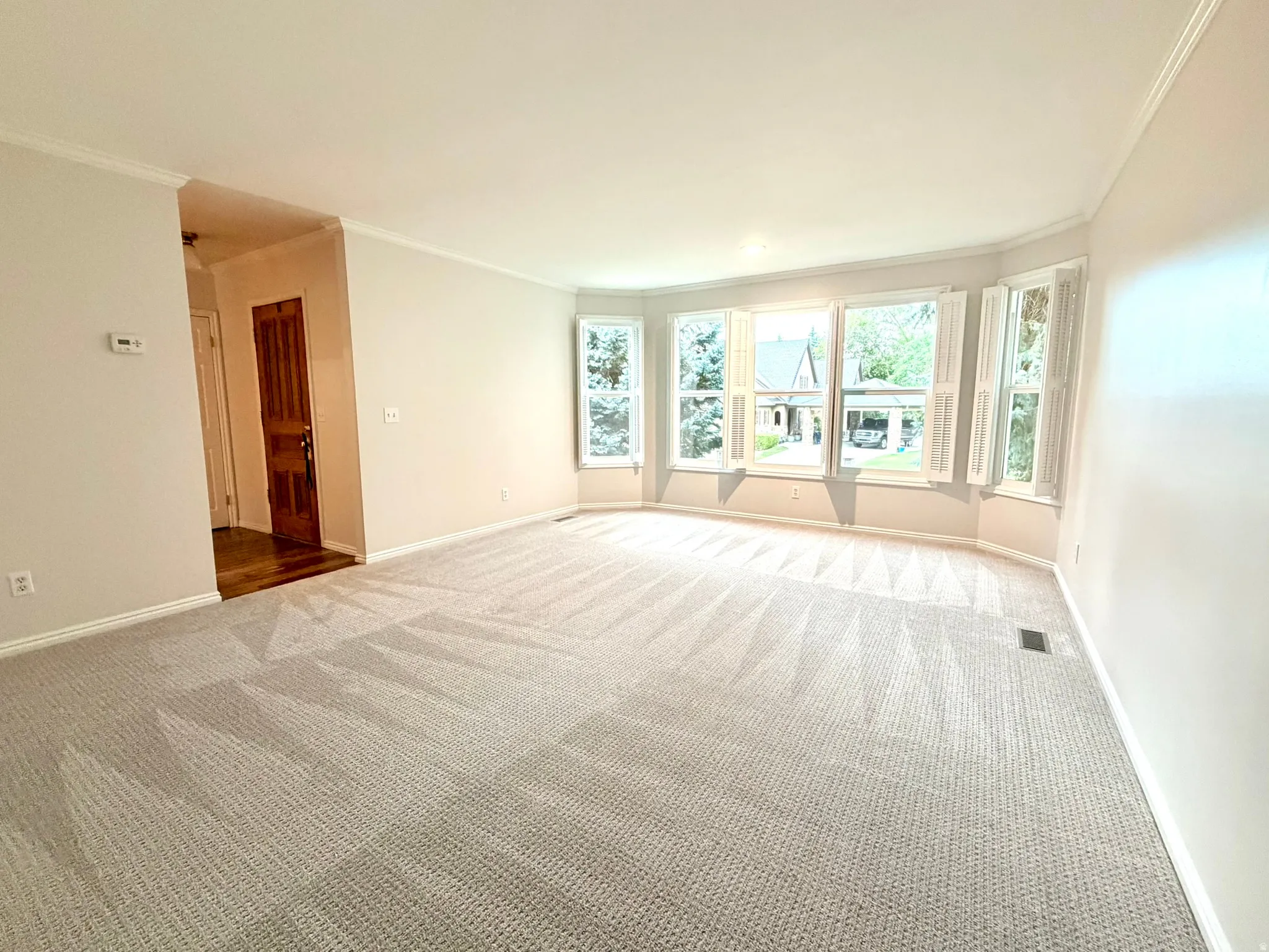 Spacious room featuring light-colored walls and crown molding