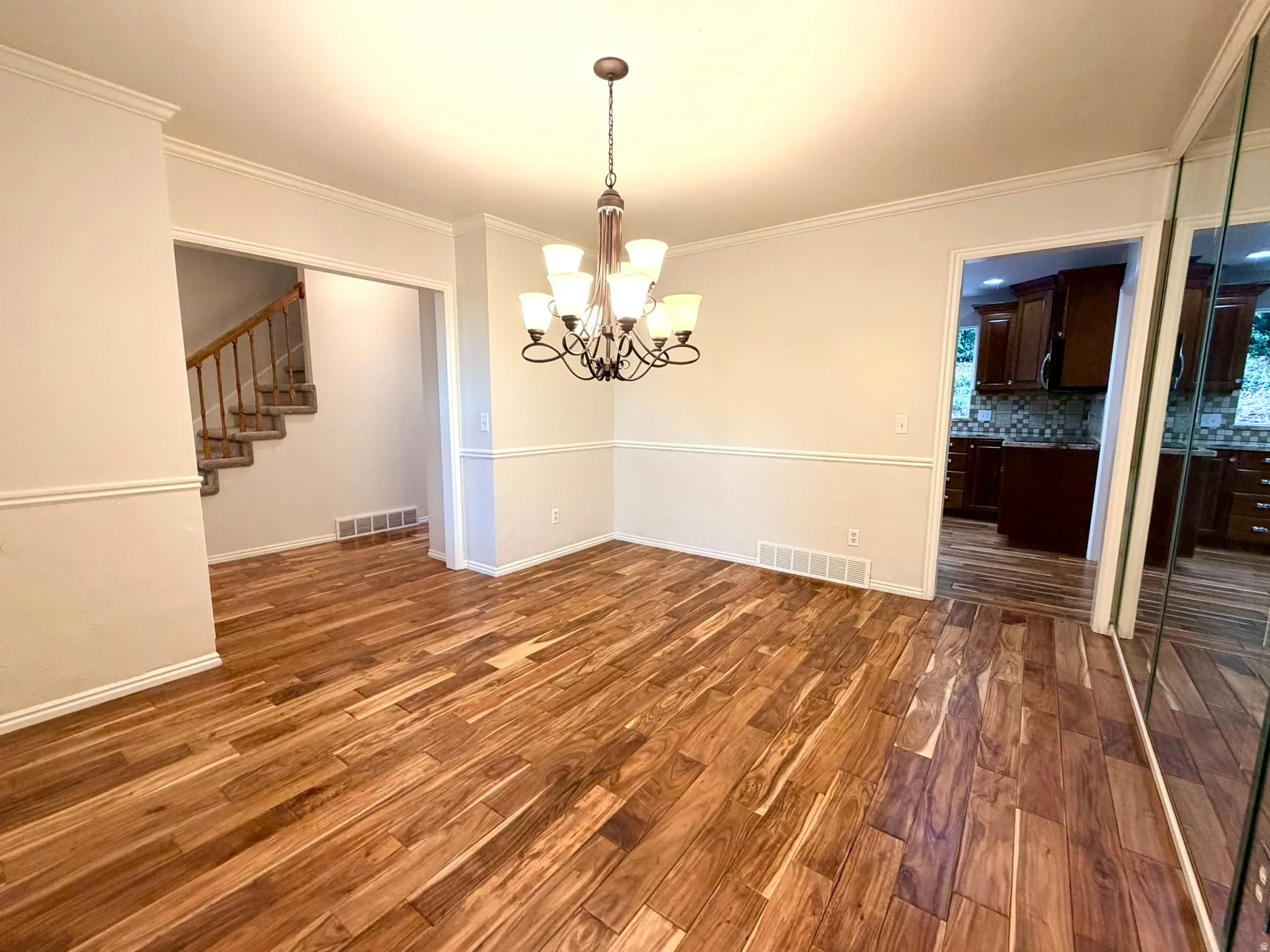 Spacious interior featuring wood-finish flooring, an ornate chandelier, and chair rail molding