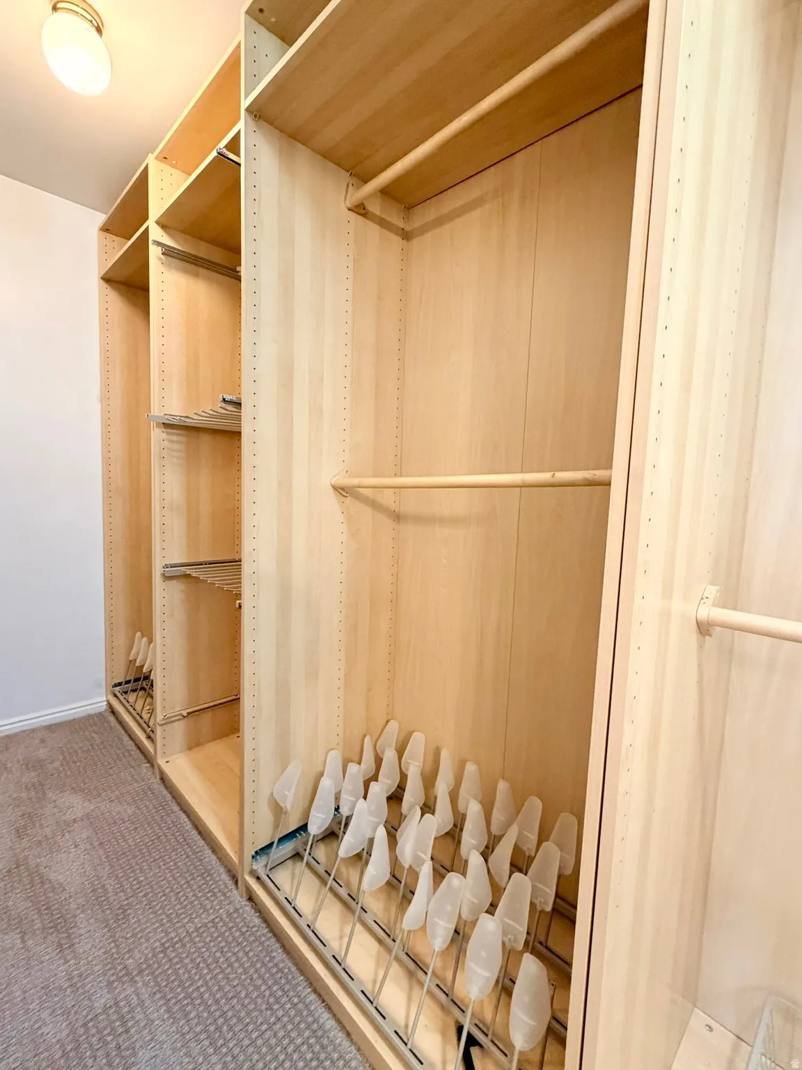 Custom closet system featuring light wood-finish cabinetry in primary bedroom