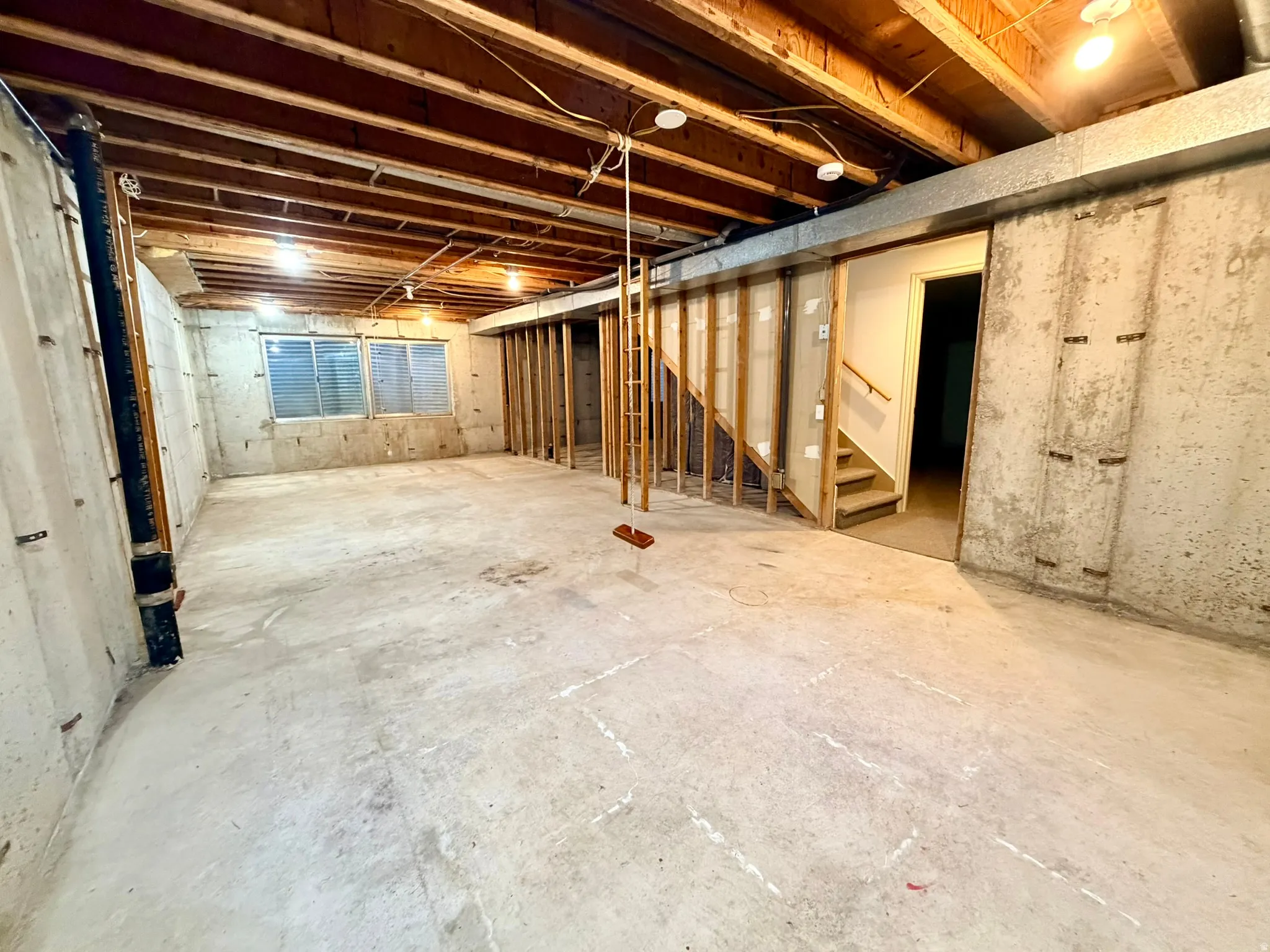 Unfinished basement with concrete flooring and exposed ceiling joists
