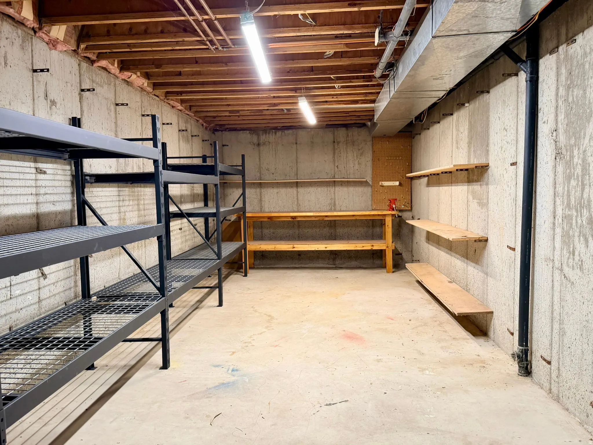 Unfinished basement featuring concrete walls, exposed ceiling joists, and a concrete floor