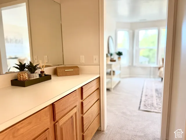 Warm wood-finish cabinetry with a light countertop and mirror
