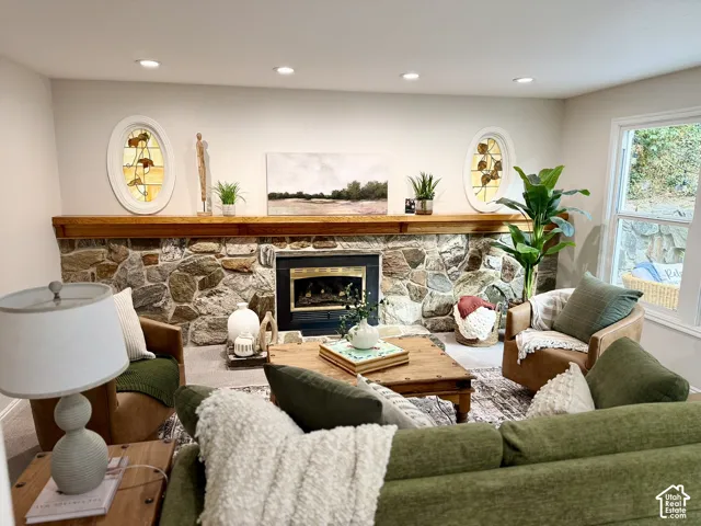 Stone-faced fireplace with a wood mantel, recessed lighting, and dual oval stained glass windows