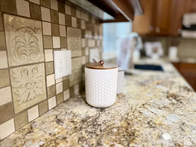 Granite countertops with a mosaic tile backsplash featuring decorative relief tiles and wood-finish cabinetry