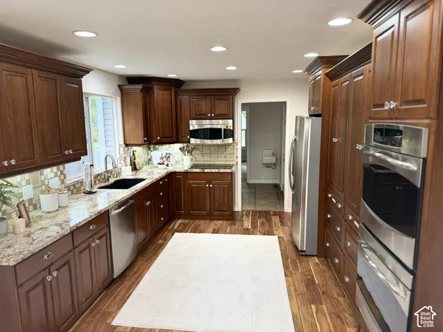Kitchen featuring wood-finish flooring, recessed lighting, and rich wood cabinetry with crown molding