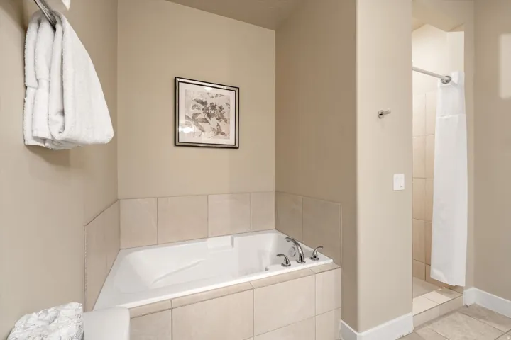 Soaking tub with a tiled surround, chrome fixtures, and a freestanding shower stall featuring tile-lined walls