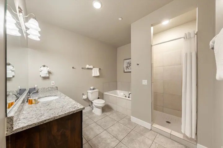 Bathroom featuring a dark wood-finish vanity with a light-toned countertop, an undermount sink, and a large mirror