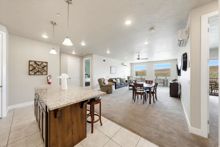 Spacious open-concept living area featuring a kitchen island with stone countertop, tile flooring, recessed lighting, and large windows with distant landscape