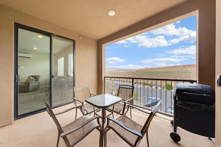 Private balcony featuring an open-air design, dark metal railing, and desert landscape beyond