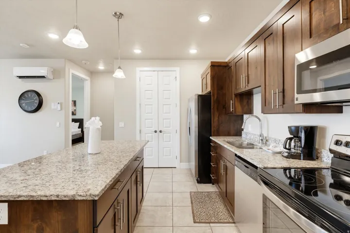 Well-appointed kitchen featuring a large island with a light-toned countertop, coordinating perimeter countertops, and rich wood-finish cabinetry