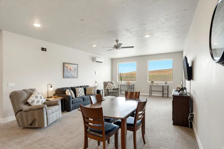 Expansive open-concept living space featuring neutral carpeting, recessed lighting, and a ceiling fan