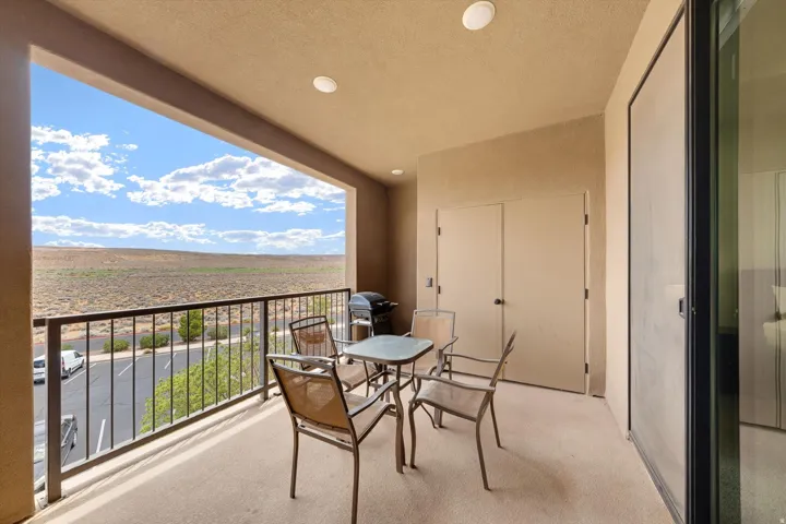 Covered balcony featuring a desert landscape backdrop, recessed ceiling lights, an exterior storage closet, and a sliding glass door