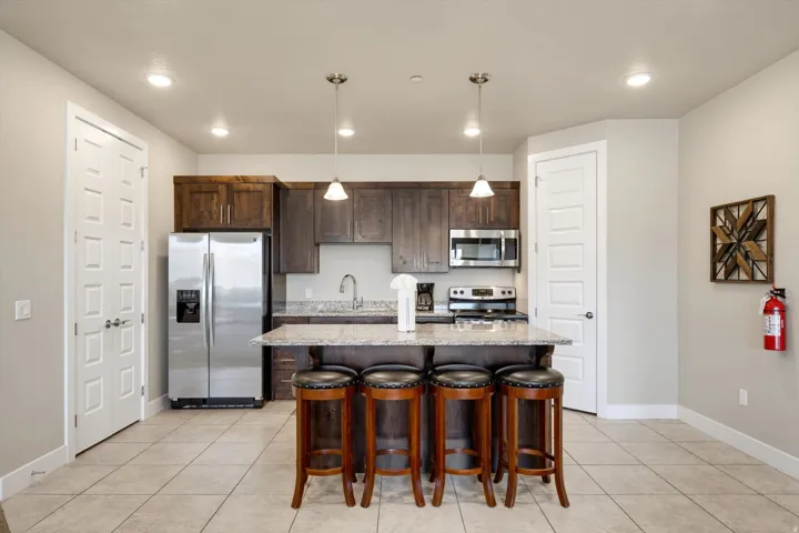 Modern kitchen featuring dark wood cabinetry, stainless steel appliances, granite countertops, and a central island with pendant lighting