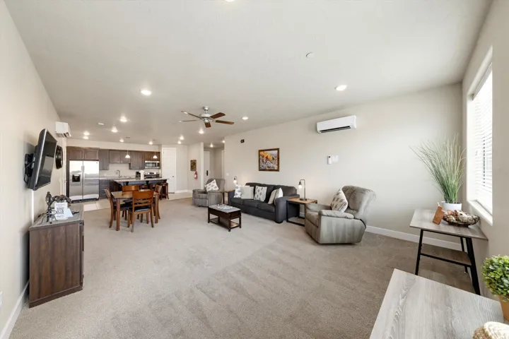 Open-concept living space featuring neutral carpet, recessed lighting, and a ceiling fan