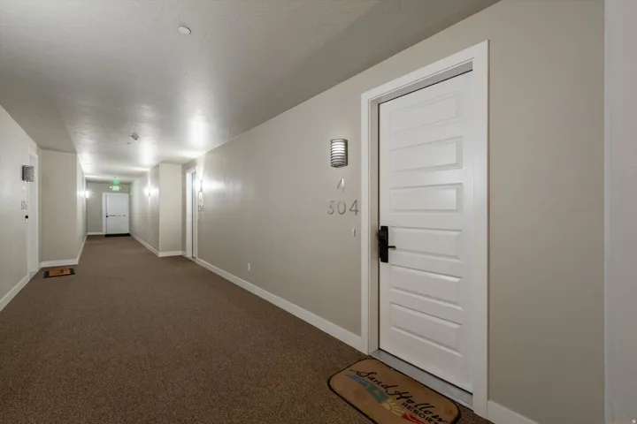 Corridor featuring neutral wall paint, carpet flooring, recessed lighting, and individual unit entrance with panel door