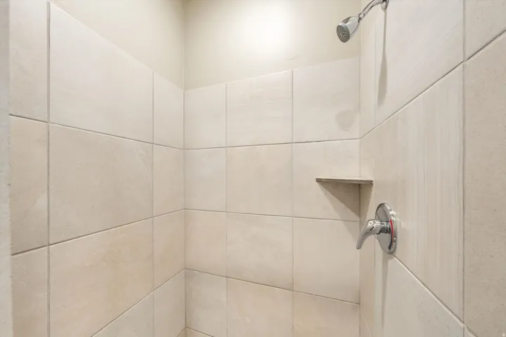 Shower enclosure featuring light-toned rectangular tile walls