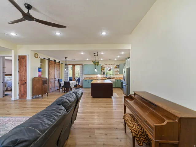 Open-concept living area with wood-finish flooring, recessed lighting, and a modern ceiling fan