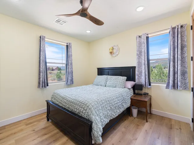Interior room featuring wood-finish flooring, two large windows with exterior scenery, a ceiling fan with integrated lighting, and recessed ceiling lights