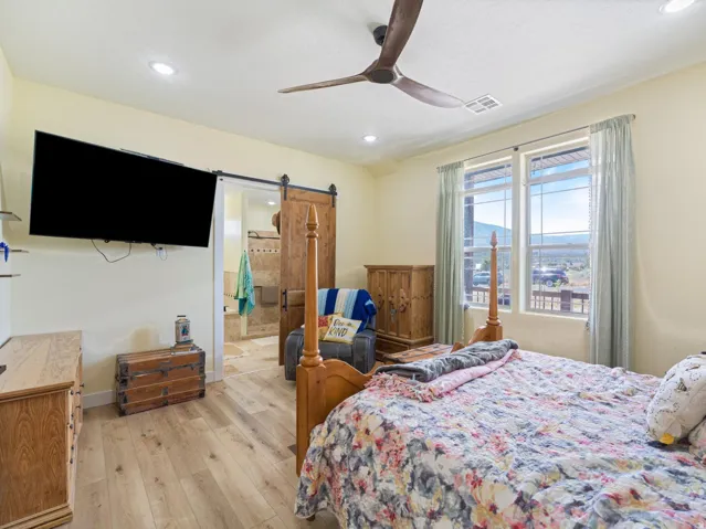 Spacious bedroom featuring wood-finish flooring and a ceiling fan