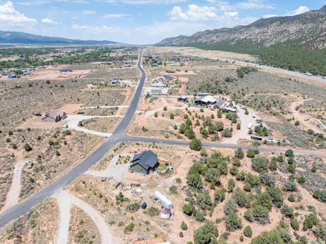 Expansive aerial landscape featuring a paved road, scattered residential properties, and natural desert vegetation