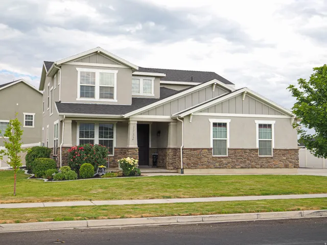 Two-story residence featuring a stucco and stone facade with gabled rooflines